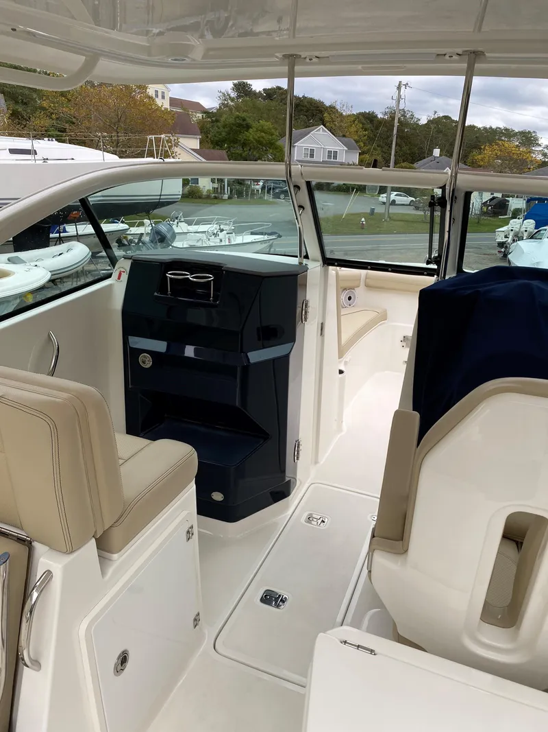 Slide: The Image of 2021 Pursuit DC 235 Dual Console boat interior with beige seating and modern dashboard. - 13