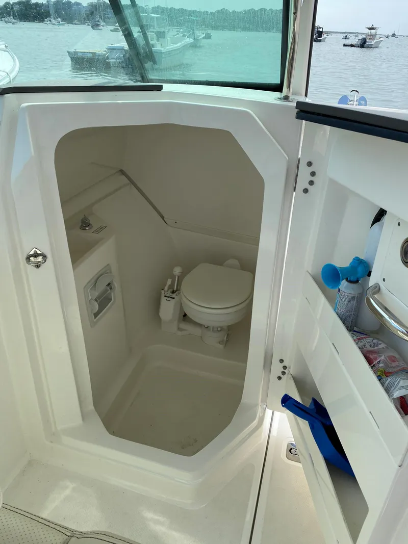 Slide: The Image of 2021 Pursuit DC 235 Dual Console boat interior with compact marine toilet. - 15