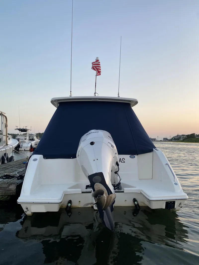 Slide: The Image of 2021 Pursuit DC 235 Dual Console boat docked with American flag at sunset. - 21