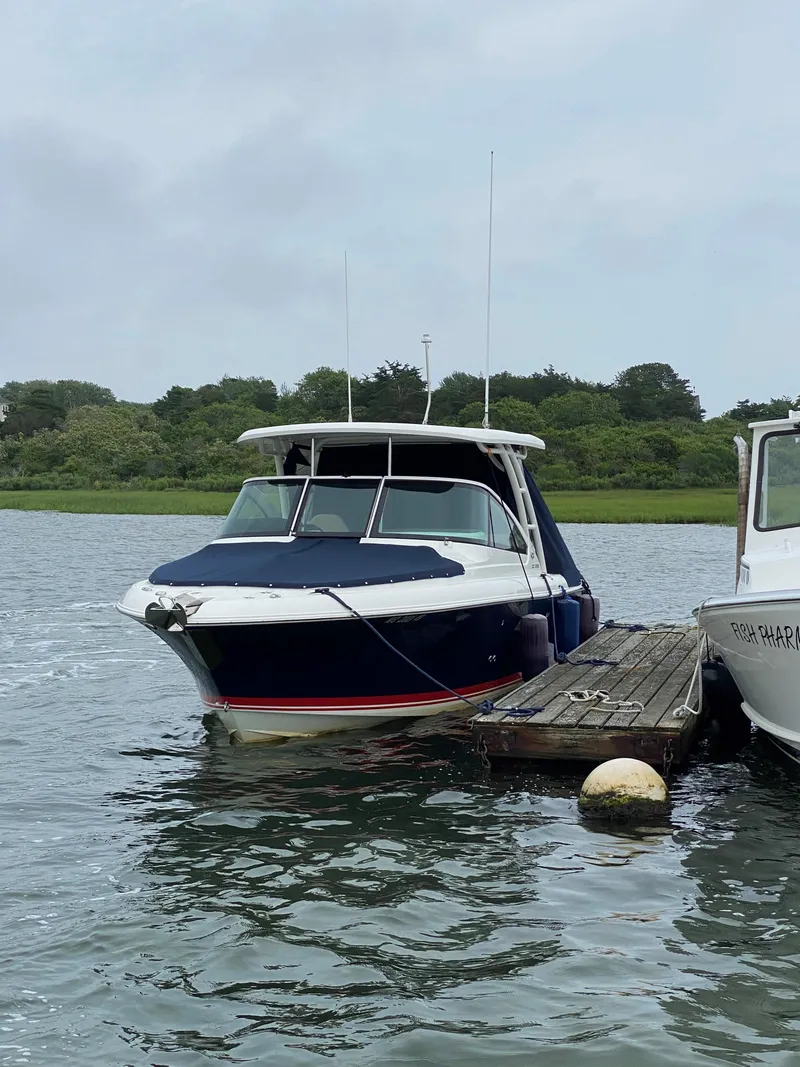 Slide: The Image of 2021 Pursuit DC 235 Dual Console boat docked on a calm lake. - 22