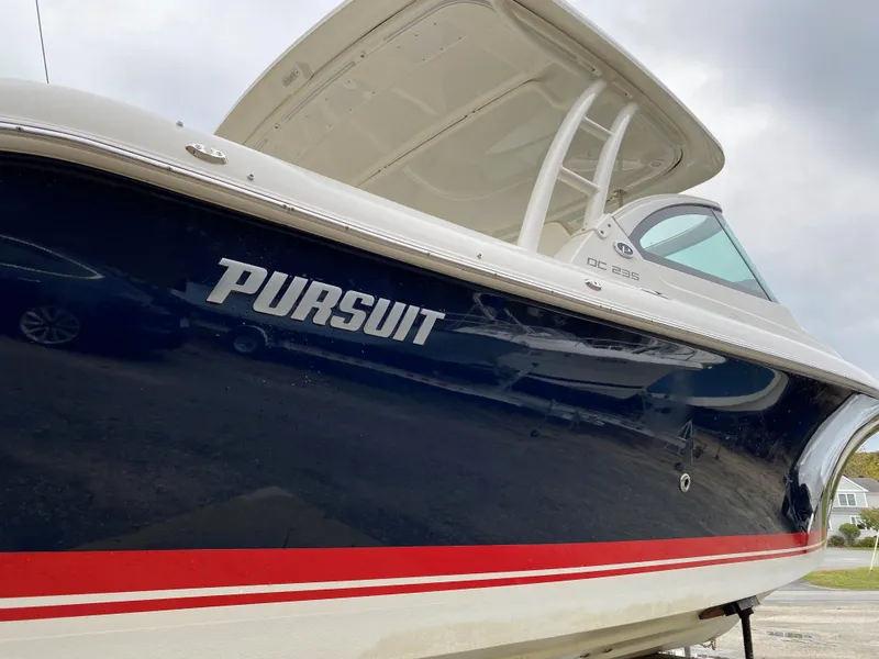 Slide: The Image of 2021 Pursuit DC 235 Dual Console boat with sleek design and navy blue hull. - 24