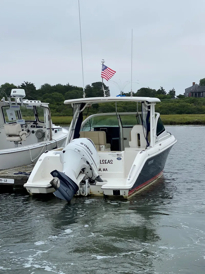 Slide: The Image of 2021 Pursuit DC 235 Dual Console boat docked in a serene waterway. - 4