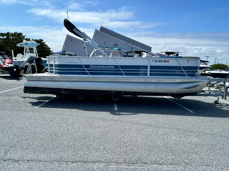 Slide: The Image of 2024 Berkshire 24CL LE 2.75 pontoon boat parked in a lot under a clear sky. - 0