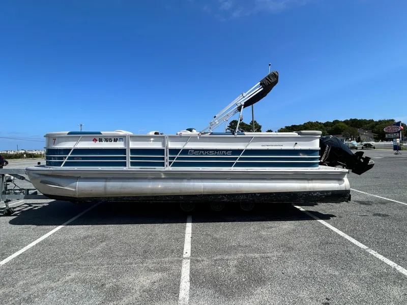 Slide: The Image of 2024 Berkshire 24CL LE 2.75 pontoon boat parked in a lot under clear blue sky. - 4
