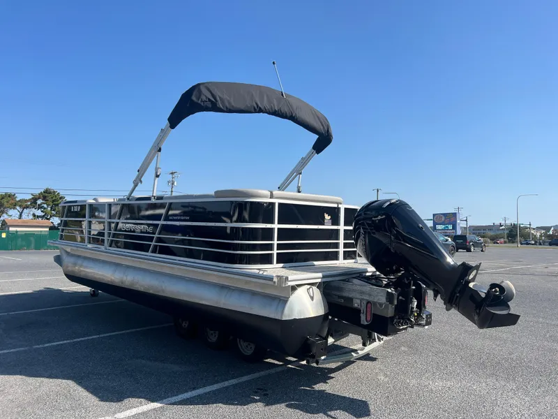 Slide: The Image of 2024 Berkshire 24CL LE 2.75 pontoon boat with canopy and outboard motor in parking lot. - 2