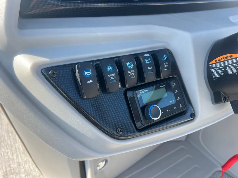 Slide: The Image of Control panel of 2024 Berkshire 24RFX LE 2.75 boat with switches and audio system. - 13