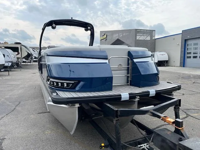 Slide: The Image of 2025 Harris Grand Mariner 250 pontoon boat on trailer, parked in a lot. - 2