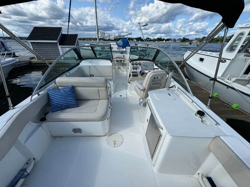 Slide: The Image of 2013 Boston Whaler 270 Vantage boat interior with seating and helm, docked by the water. - 10