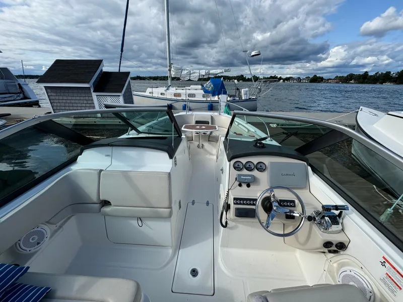 Slide: The Image of 2013 Boston Whaler 270 Vantage boat interior with steering wheel and dashboard, docked by the water. - 14