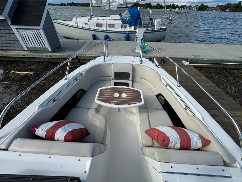Slide: The Image of 2013 Boston Whaler 270 Vantage boat with cushioned seating and striped pillows at dock. - 17