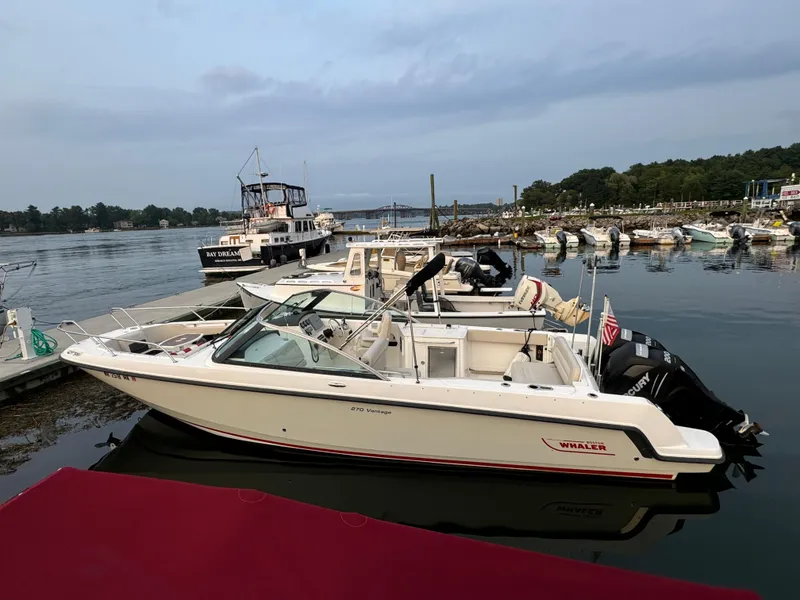 Slide: The Image of 2013 Boston Whaler 270 Vantage boat docked in a serene marina setting. - 2