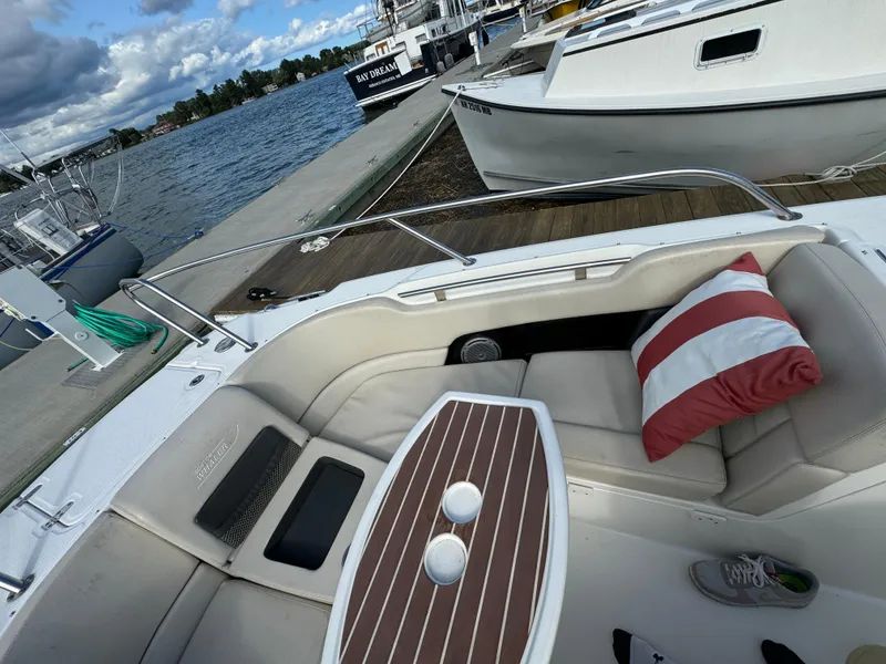 Slide: The Image of 2013 Boston Whaler 270 Vantage boat interior with seating and table, docked by the water. - 20