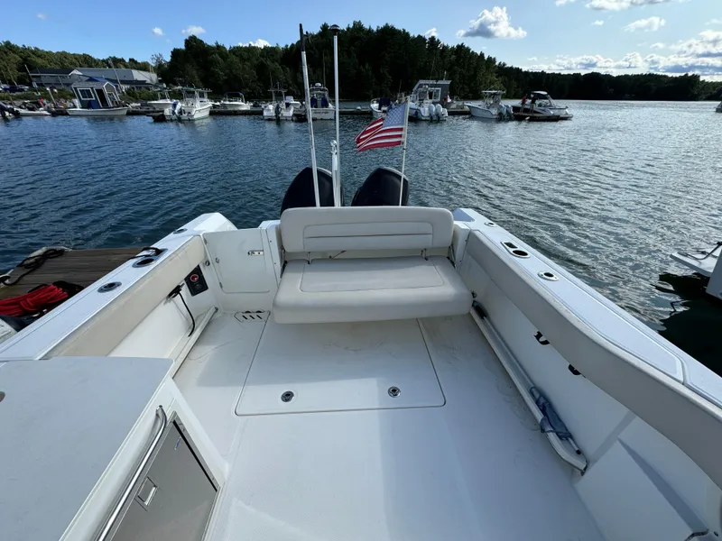 Slide: The Image of 2013 Boston Whaler 270 Vantage boat interior with seating, docked on a scenic lake. - 7