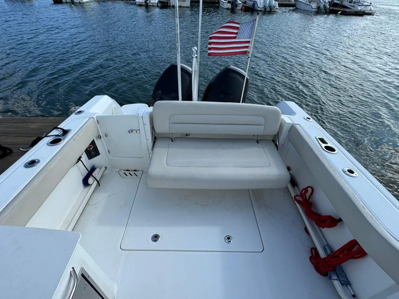 Slide: The Image of 2013 Boston Whaler 270 Vantage boat with American flag, docked by the water. - 8