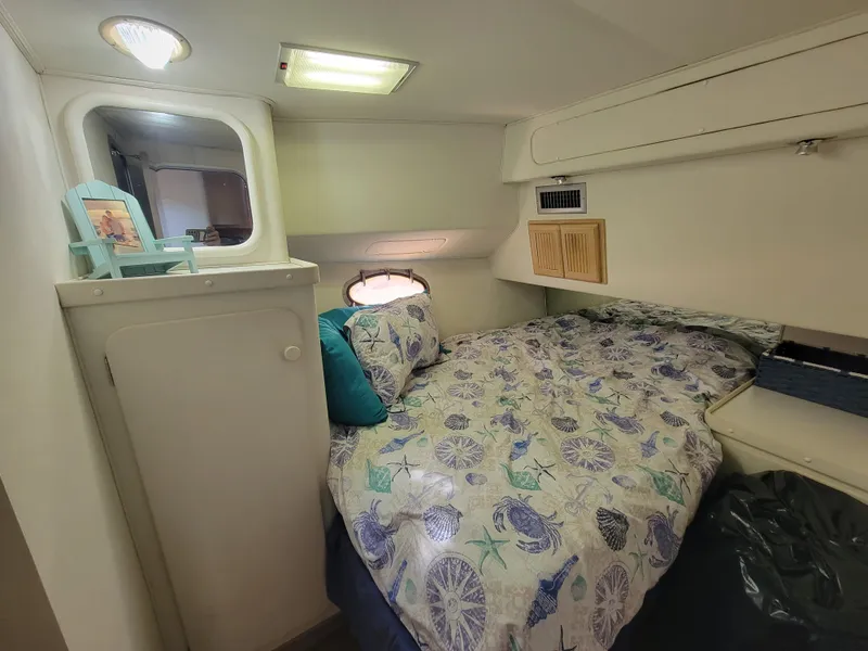 Slide: The Image of 1989 Trojan 46 Sportfish cabin with cozy bed, floral bedding, and soft lighting. - 18