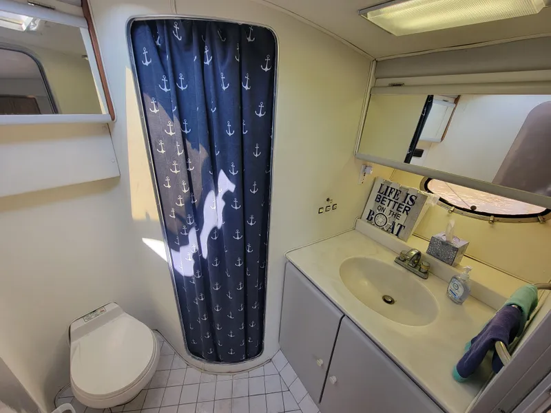 Slide: The Image of 1989 Trojan 46 Sportfish bathroom with anchor-themed shower curtain and nautical decor. - 20