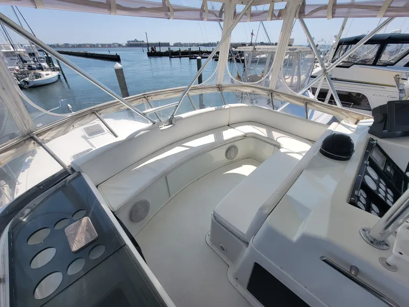 Slide: The Image of 1989 Trojan 46 Sportfish yacht cockpit with white seating, overlooking marina and water. - 25