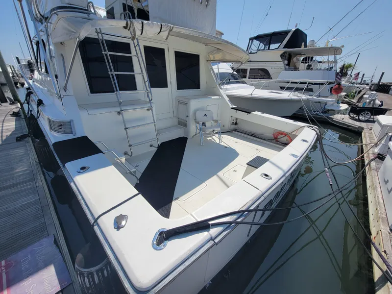 Slide: The Image of 1989 Trojan 46 Sportfish yacht docked, featuring spacious deck and modern design. - 6