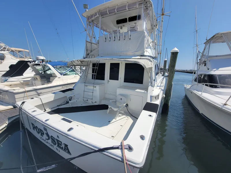 Slide: The Image of 1989 Trojan 46 Sportfish boat docked at marina, featuring spacious deck and flybridge. - 7