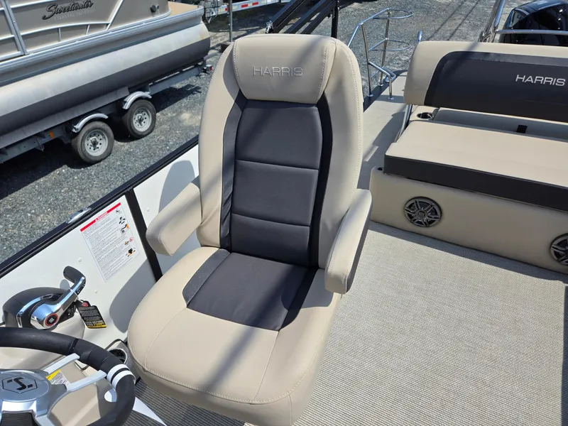 Slide: The Image of 2025 Harris Cruiser 210 boat seat, beige and black upholstery, steering wheel visible. - 10