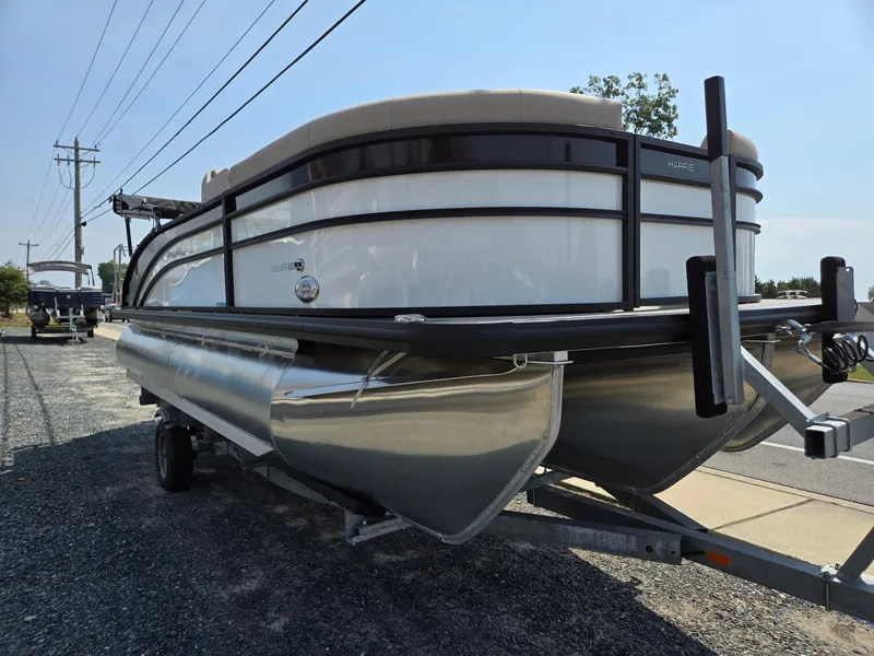 Slide: The Image of 2025 Harris Cruiser 210 pontoon boat on trailer, parked outdoors. - 2