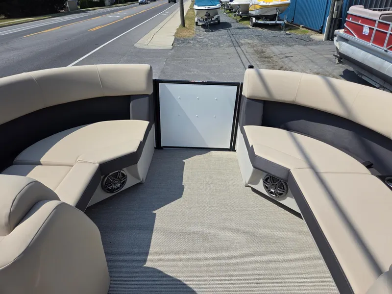 Slide: The Image of 2025 Harris Cruiser 210 boat interior with beige seating and speakers, parked near a road. - 28