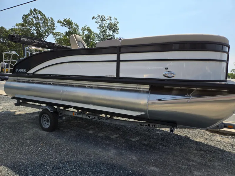 Slide: The Image of 2025 Harris Cruiser 210 pontoon boat on trailer, parked outdoors. - 3
