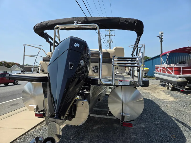 Slide: The Image of 2025 Harris Cruiser 210 pontoon boat with powerful outboard motor, parked on gravel. - 5
