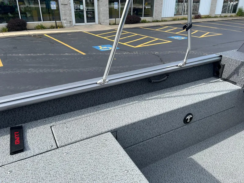 Slide: The Image of 2025 Lund 1775 Impact XS Sport boat interior, featuring gray seating and storage compartments. - 16