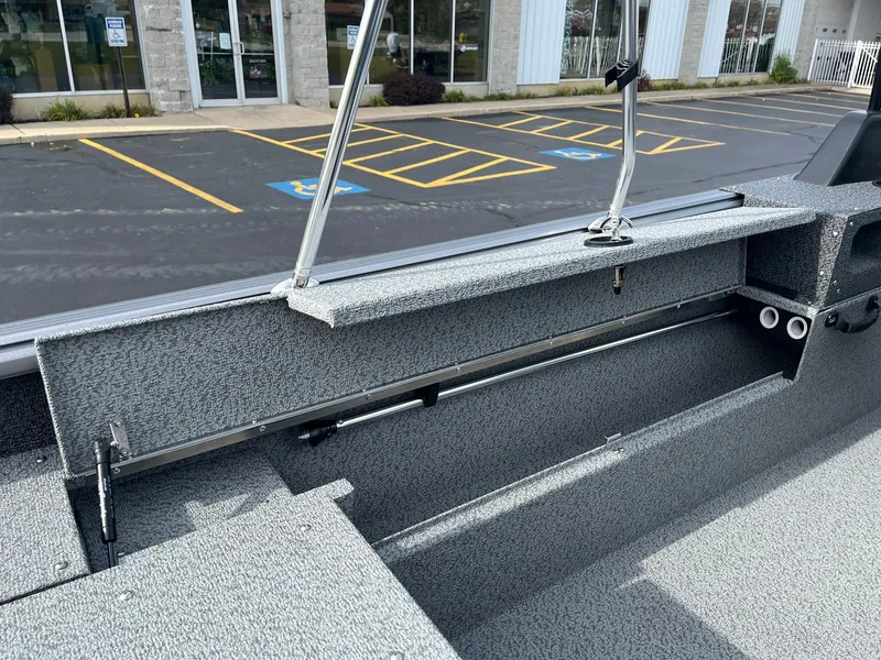 Slide: The Image of 2025 Lund 1775 Impact XS Sport boat interior with storage compartments, parked in a lot. - 17