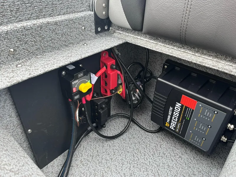 Slide: The Image of 2025 Lund 1775 Impact XS Sport boat battery compartment with wiring and charger. - 22