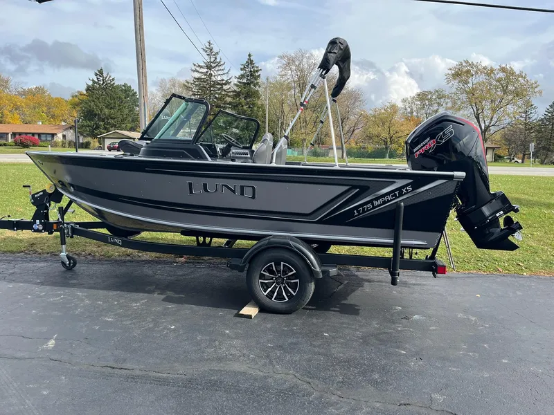 Slide: The Image of 2025 Lund 1775 Impact XS Sport boat on trailer, parked outdoors. - 3