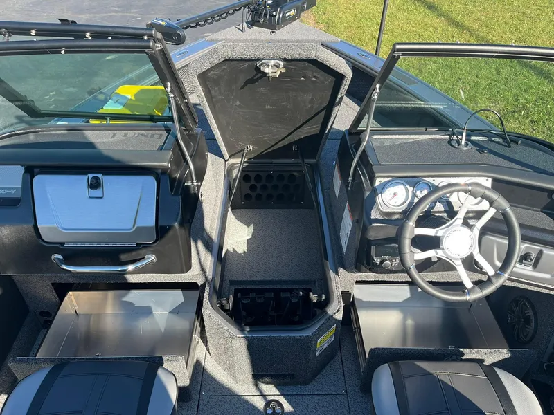 Slide: The Image of 2025 Lund 1875 Pro-V boat interior with open storage compartments and steering wheel. - 17