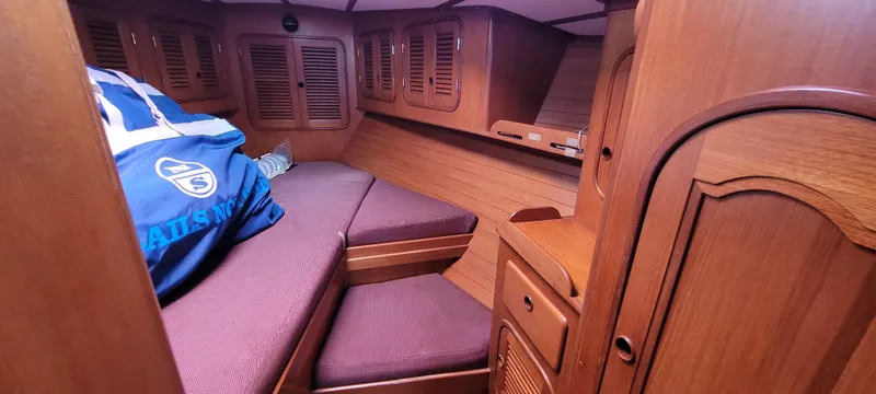 Slide: The Image of Interior of 1985 Mason 33 Sloop with wooden cabinetry and purple cushions. - 11
