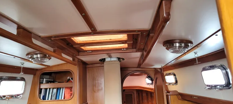 Slide: The Image of Interior of a 1985 Mason 33 Sloop, featuring wooden paneling and built-in shelving. - 14