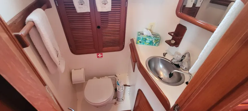 Slide: The Image of Compact bathroom in a 1985 Mason 33 Sloop, featuring a sink, toilet, and wooden cabinetry. - 18