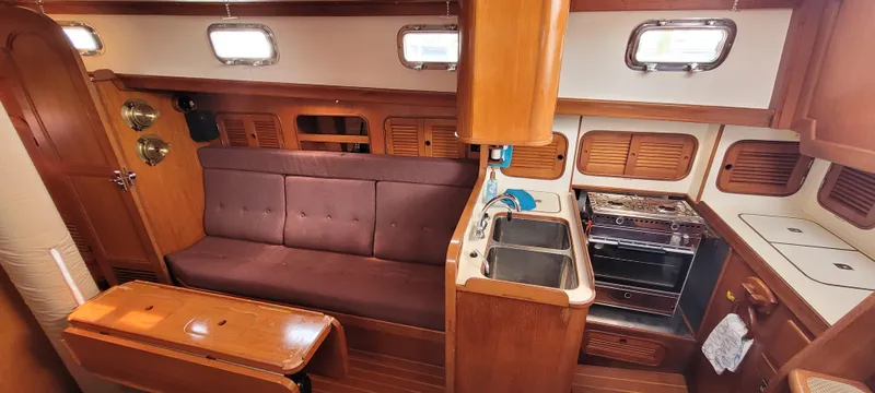 Slide: The Image of Interior of 1985 Mason 33 Sloop with wooden cabinetry and compact kitchen area. - 3