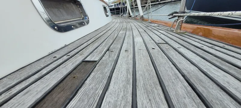 Slide: The Image of Deck of 1985 Mason 33 Sloop with wooden planks and metal fittings, docked at marina. - 36
