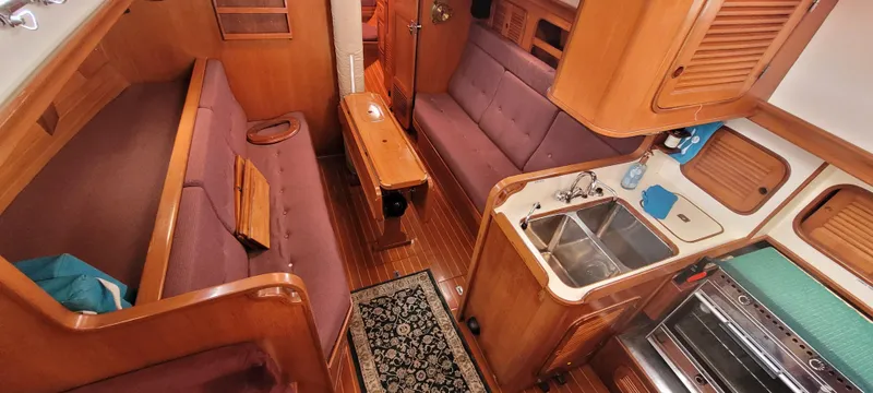 Slide: The Image of Interior of 1985 Mason 33 Sloop, featuring cozy seating, kitchen, and wooden finishes. - 4