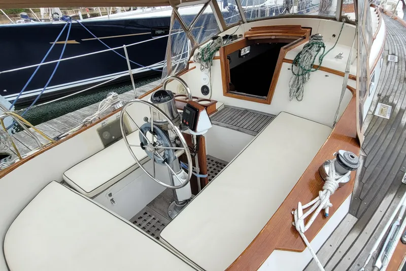 Slide: The Image of 1985 Mason 33 Sloop cockpit with steering wheel, seating, and nautical ropes. - 42