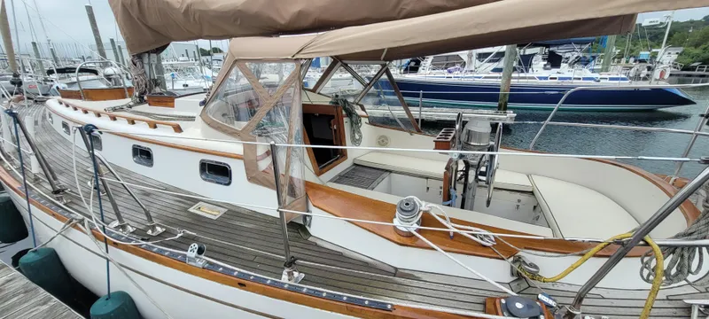 Slide: The Image of 1985 Mason 33 Sloop docked, featuring wooden deck and beige canopy. - 45