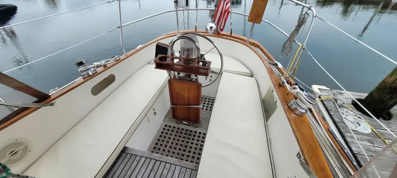 Slide: The Image of 1985 Mason 33 Sloop cockpit with wooden accents and steering wheel, docked by calm water. - 46