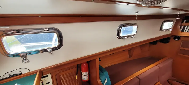 Slide: The Image of Interior of 1985 Mason 33 Sloop sailboat, featuring portholes and wooden cabinetry. - 8
