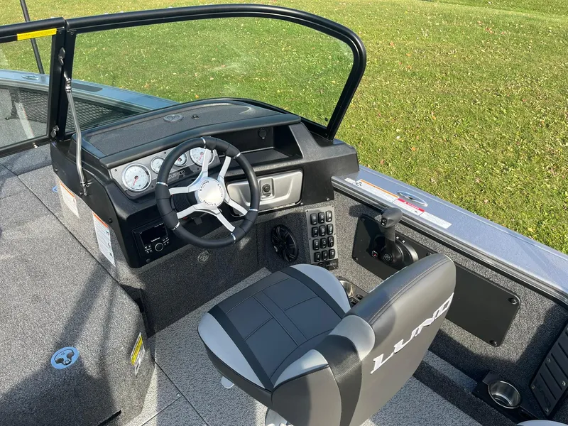 Slide: The Image of 2025 Lund 1875 Pro-V boat cockpit with steering wheel and control panel. - 14