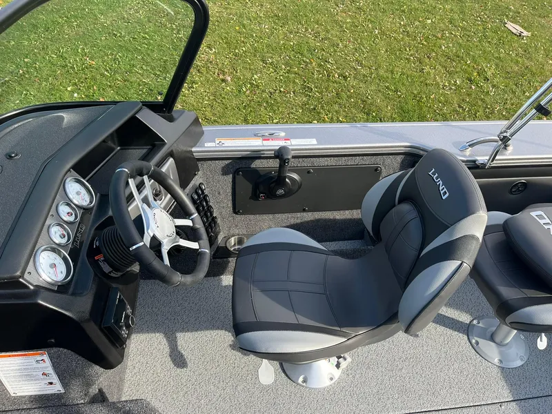 Slide: The Image of 2025 Lund 1875 Pro-V boat interior with steering wheel and cushioned seats. - 15