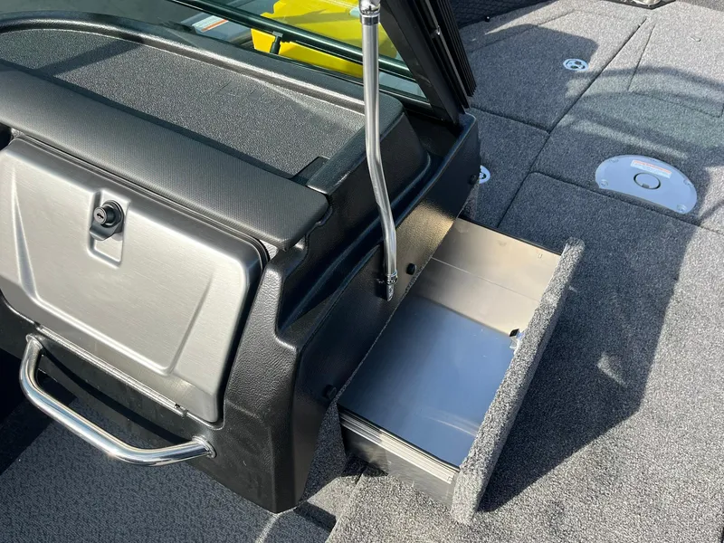 Slide: The Image of 2025 Lund 1875 Pro-V boat interior with open storage compartment and carpeted flooring. - 21