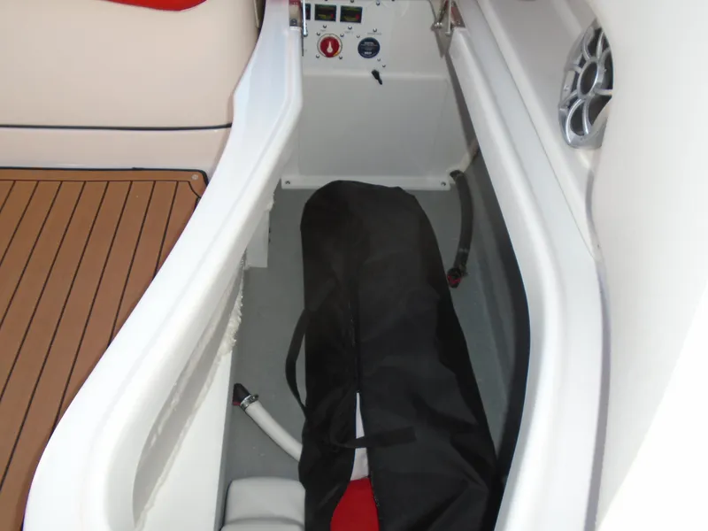 Slide: The Image of 2024 Crownline Eclipse E255 SURF boat storage compartment with teak flooring and speaker. - 13