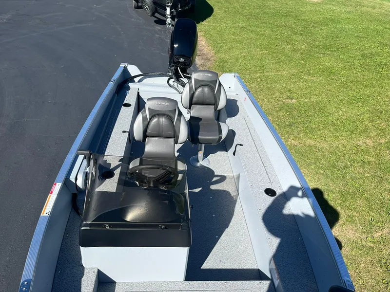 Slide: The Image of 2025 Lund 1600 Fury SS boat with dual seats and motor, parked on grass. - 14