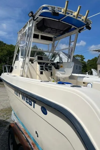 Slide: The Image of 2004 Key West 2300 WA boat with canopy, parked outdoors under a clear blue sky. - 13