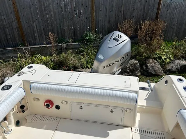 Slide: The Image of 2004 Key West 2300 WA boat with Honda outboard motor, docked near wooden fence. - 2